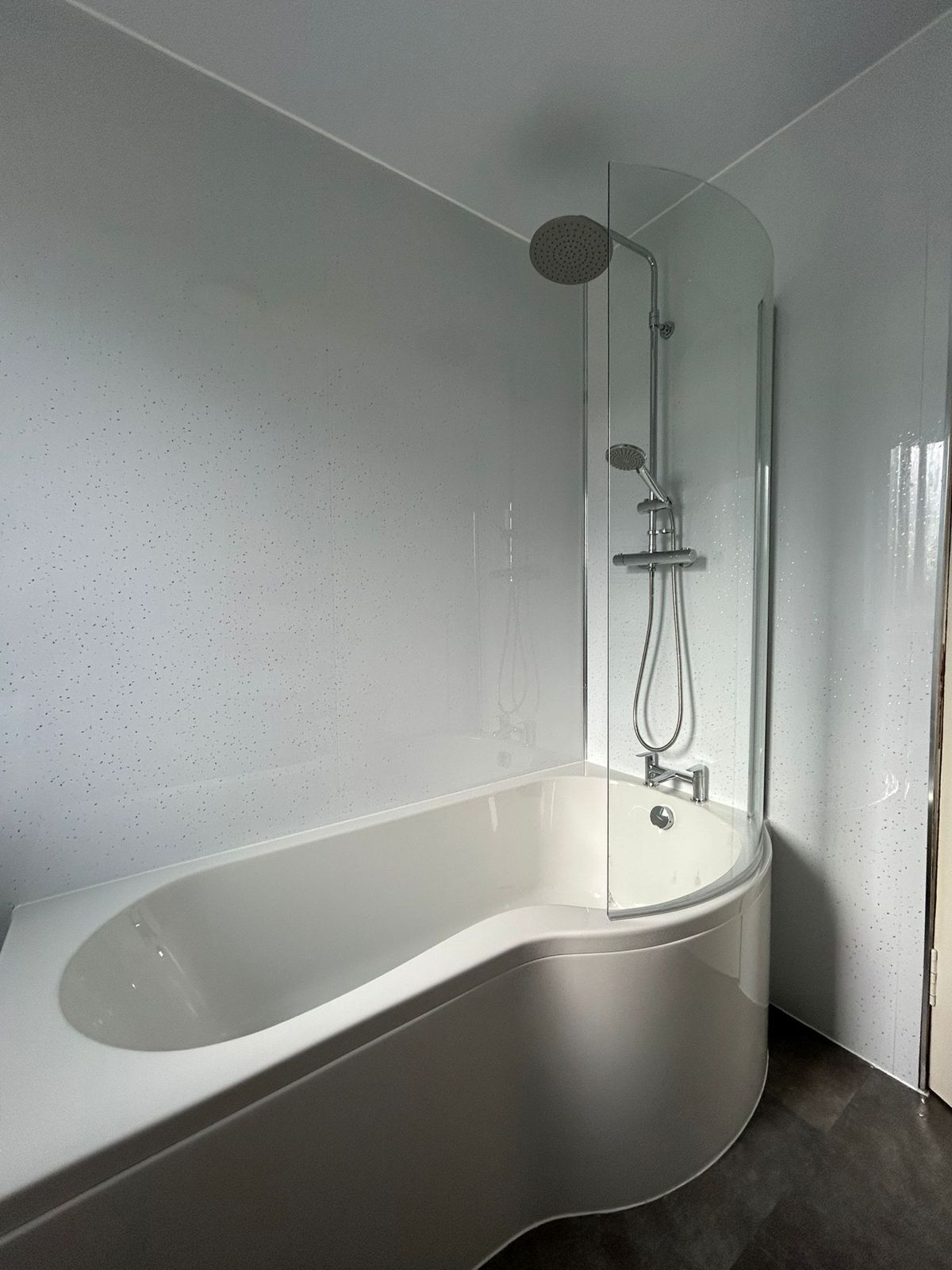 A P-shaped shower bath with a curved glass screen and overhead shower