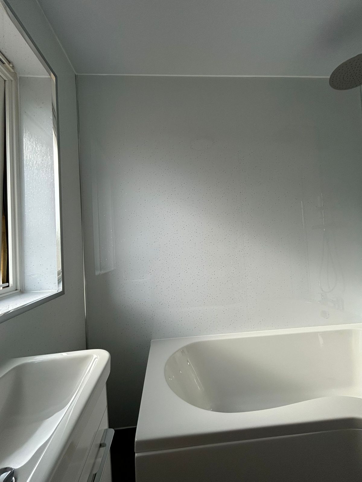 A white bath and basin fitted into the corner of a bathroom